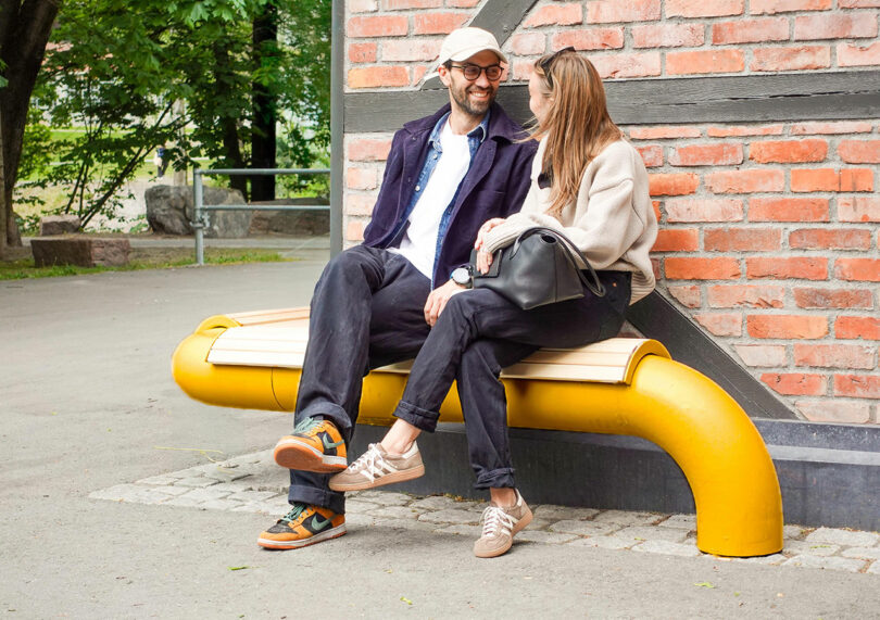 Two people engaged in conversation while sitting on a bright yellow modular bench.