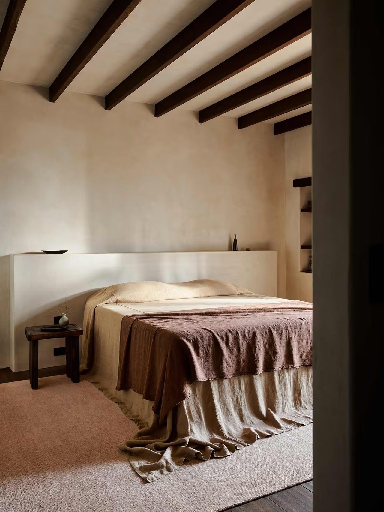 Minimalist bedroom styled with Italian washed linen sheets and a soft pink rug.