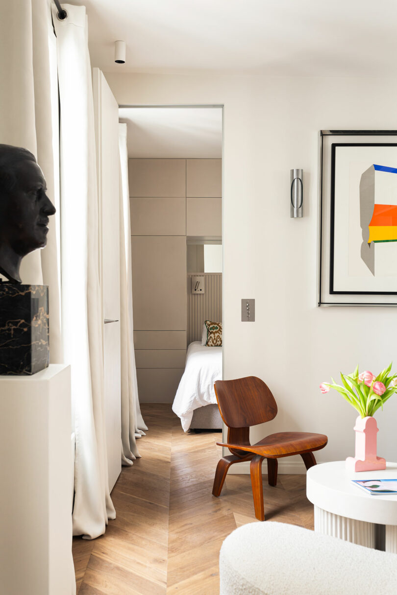 A view from the living area toward the bedroom, featuring a bust on a pedestal and contemporary wall art.