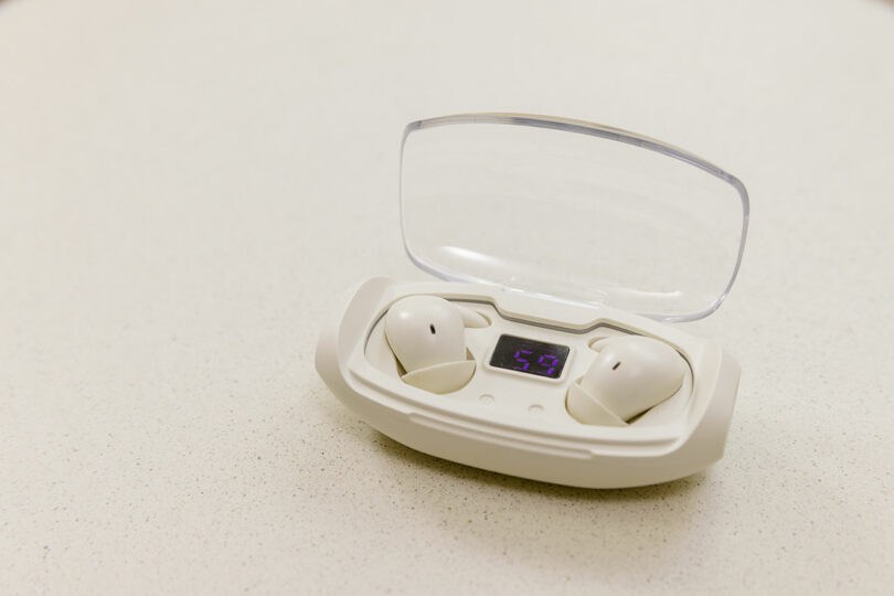 White wireless sleep earbuds in a modern charging case with a digital battery percentage display.
