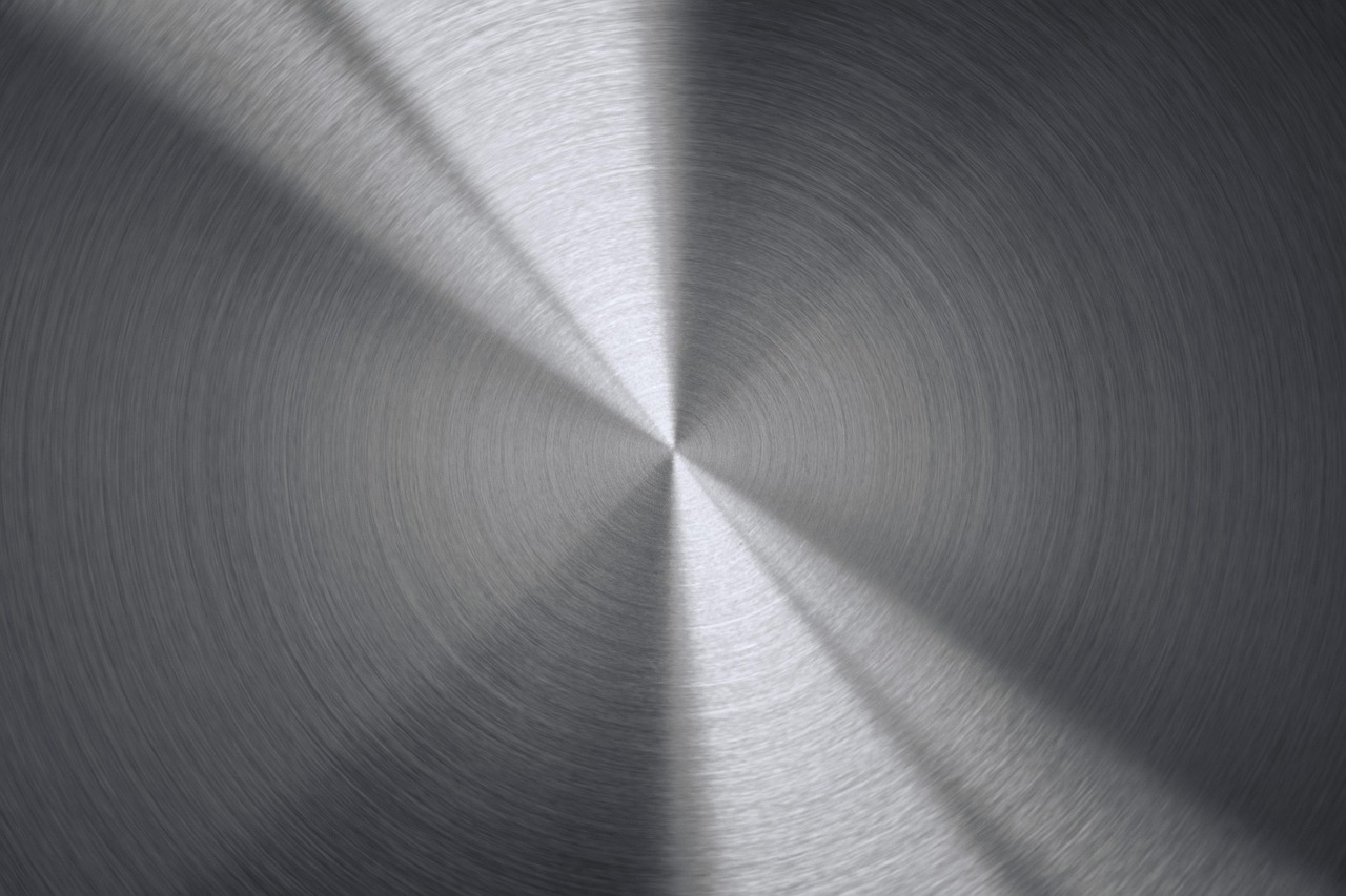 A stack of different metal baking sheets including aluminum and stainless steel.