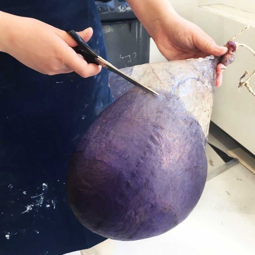 Close-up of hands cutting and shaping a purple organic material.