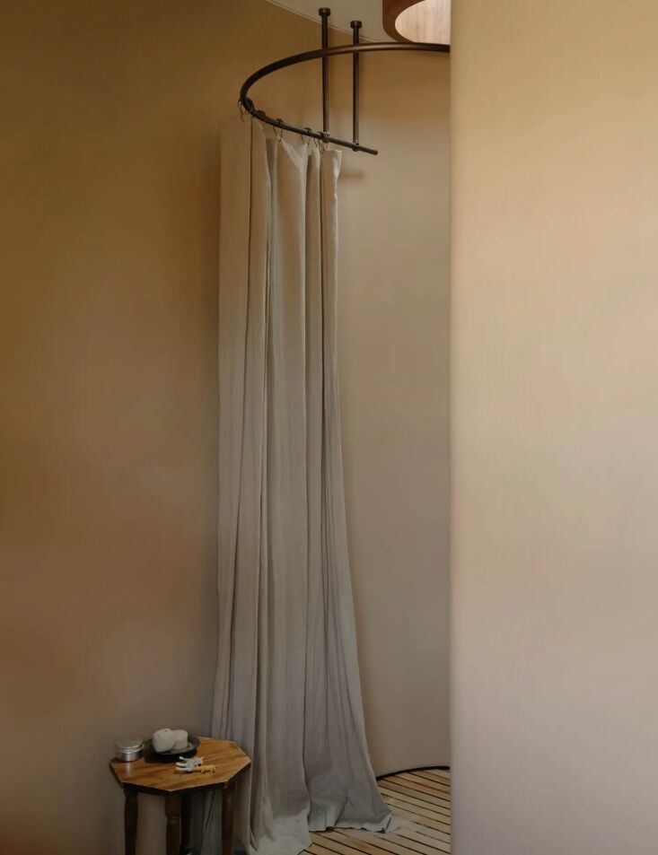 A curved shower with Tadelakt walls situated under a large circular skylight showing tree views.