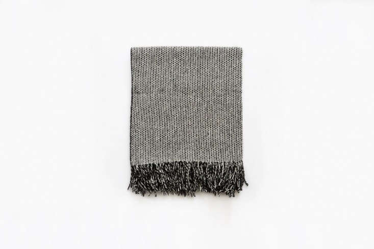 A monochrome tweed bed throw with a visible weave pattern.