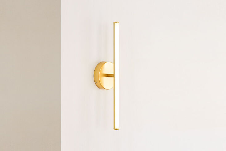 A West Elm Light Rods LED sconce in an antique brass finish.