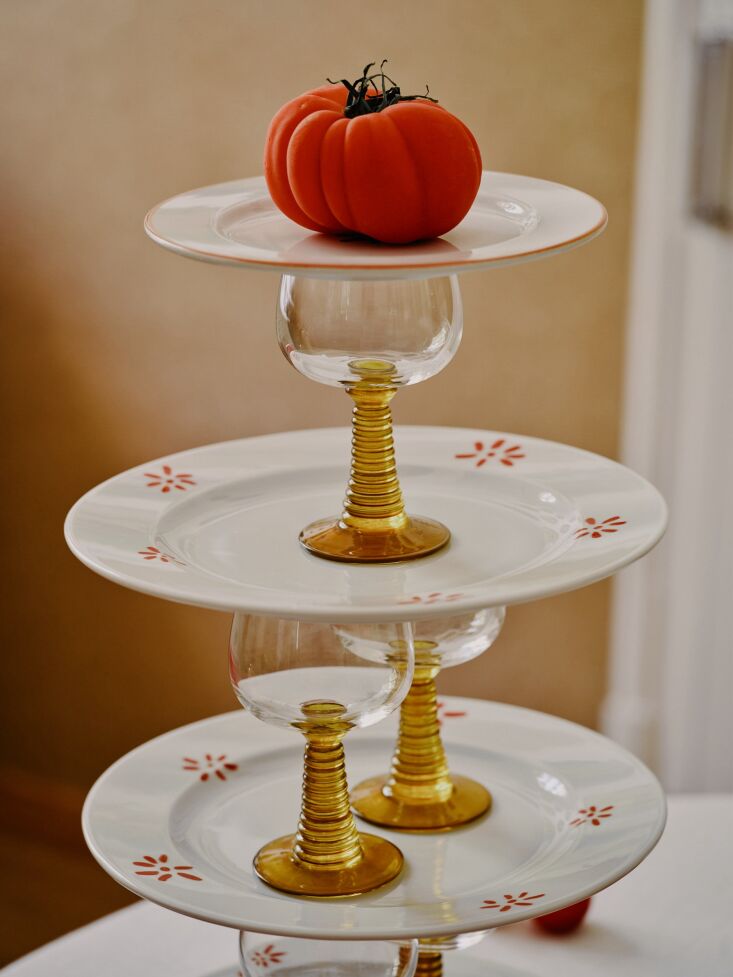 Orange swirl-base wine glasses and porcelain dinner plates on a table.