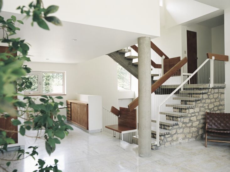 A three-story staircase made of stone and concrete with metal and wood railings.