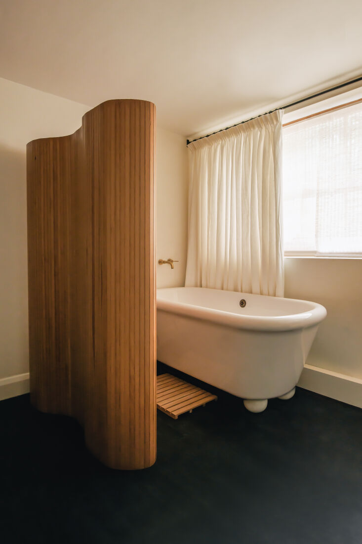 An Alvar Aalto wooden room divider separating a bedroom from a bathroom area.