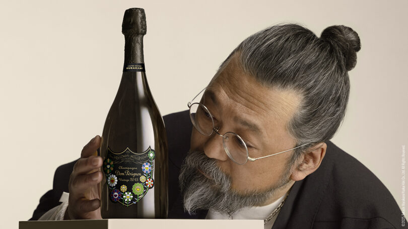 Takashi Murakami closely examining a decorated Dom Pérignon bottle.