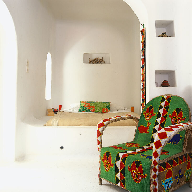 A white beaded armchair in a minimal, Moroccan-style bedroom.