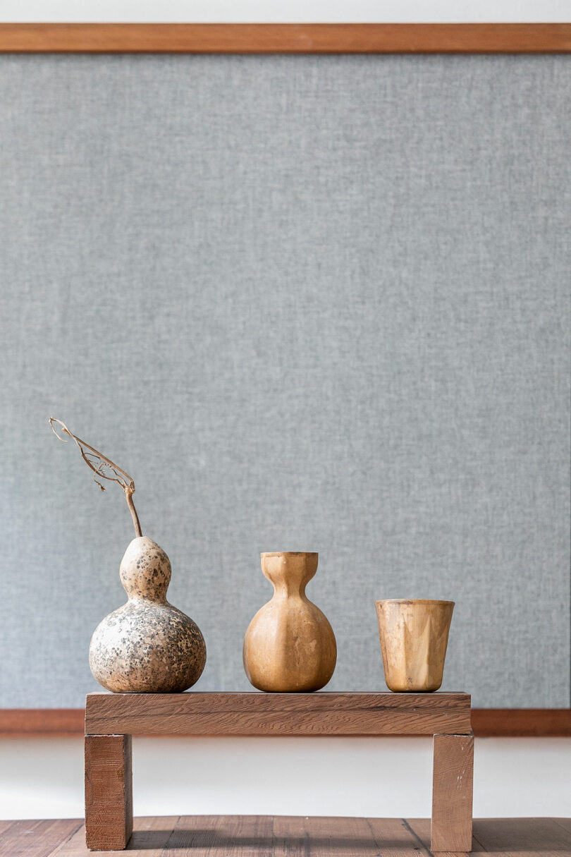 Minimalist wooden and gourd vessels displayed as decor on a wooden platform.