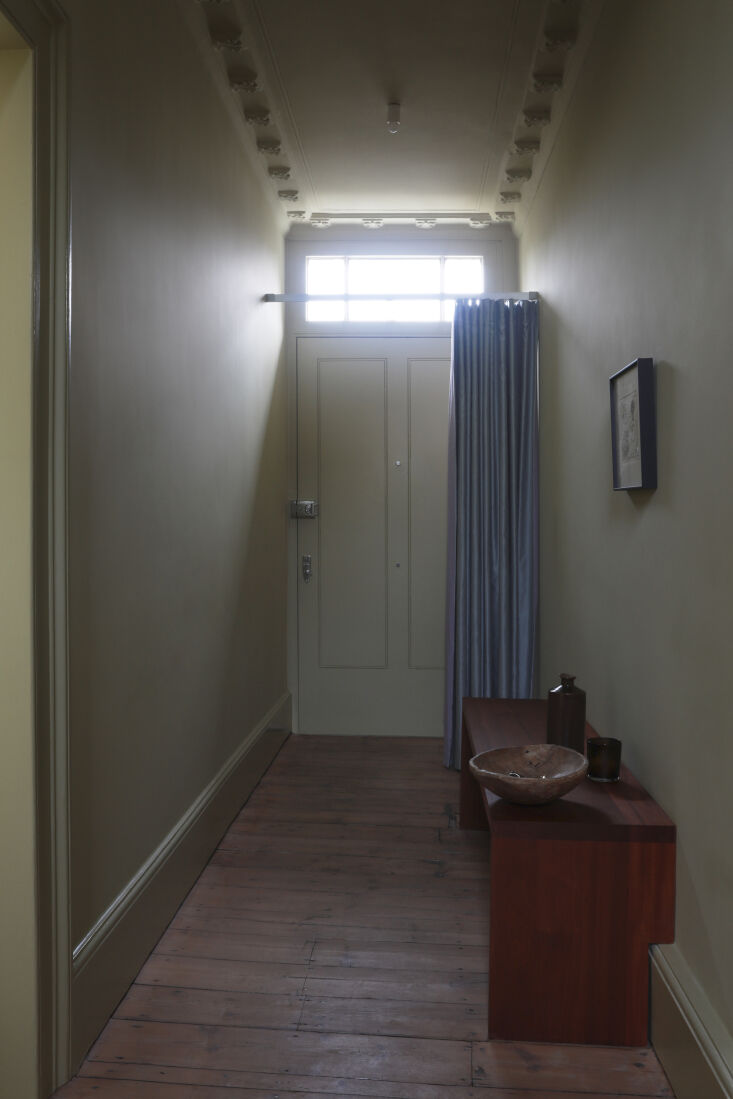 A dual-sided curtain in steel-blue satin and lilac linen hanging in a hallway.