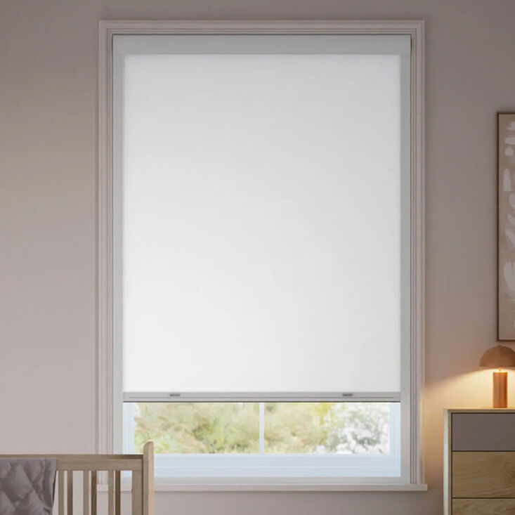 A drill-free blackout roller shade with a snap-in frame installed in a window.