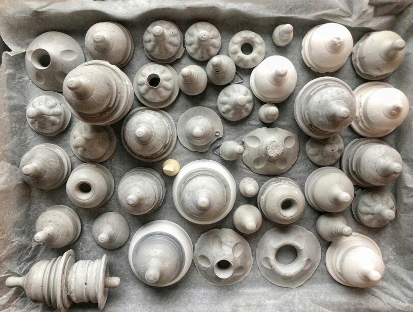 A collection of gray and white conical and cylindrical clay objects by Katherine Duclos.