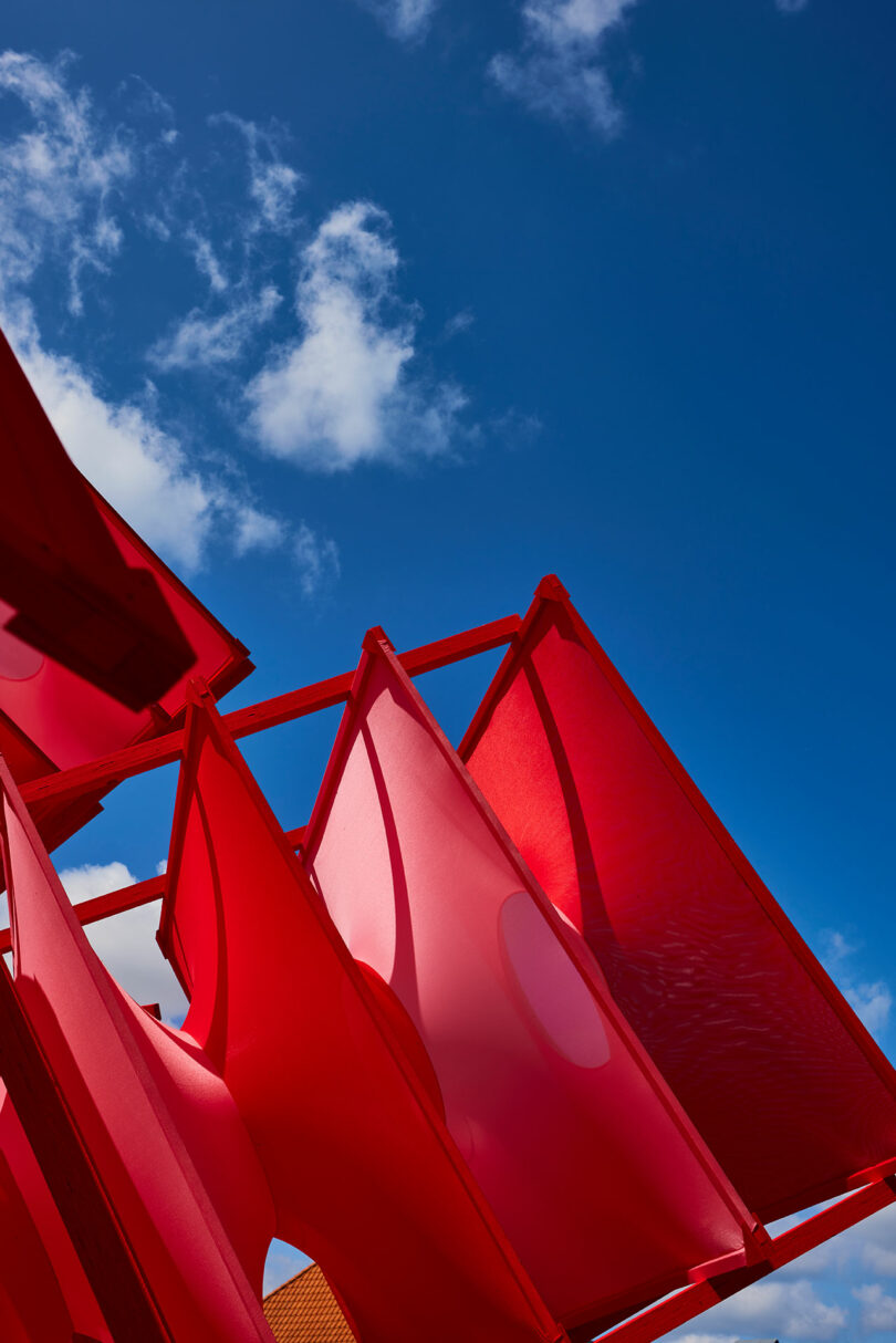 Detailed view of red fabric panels against a clear blue sky.