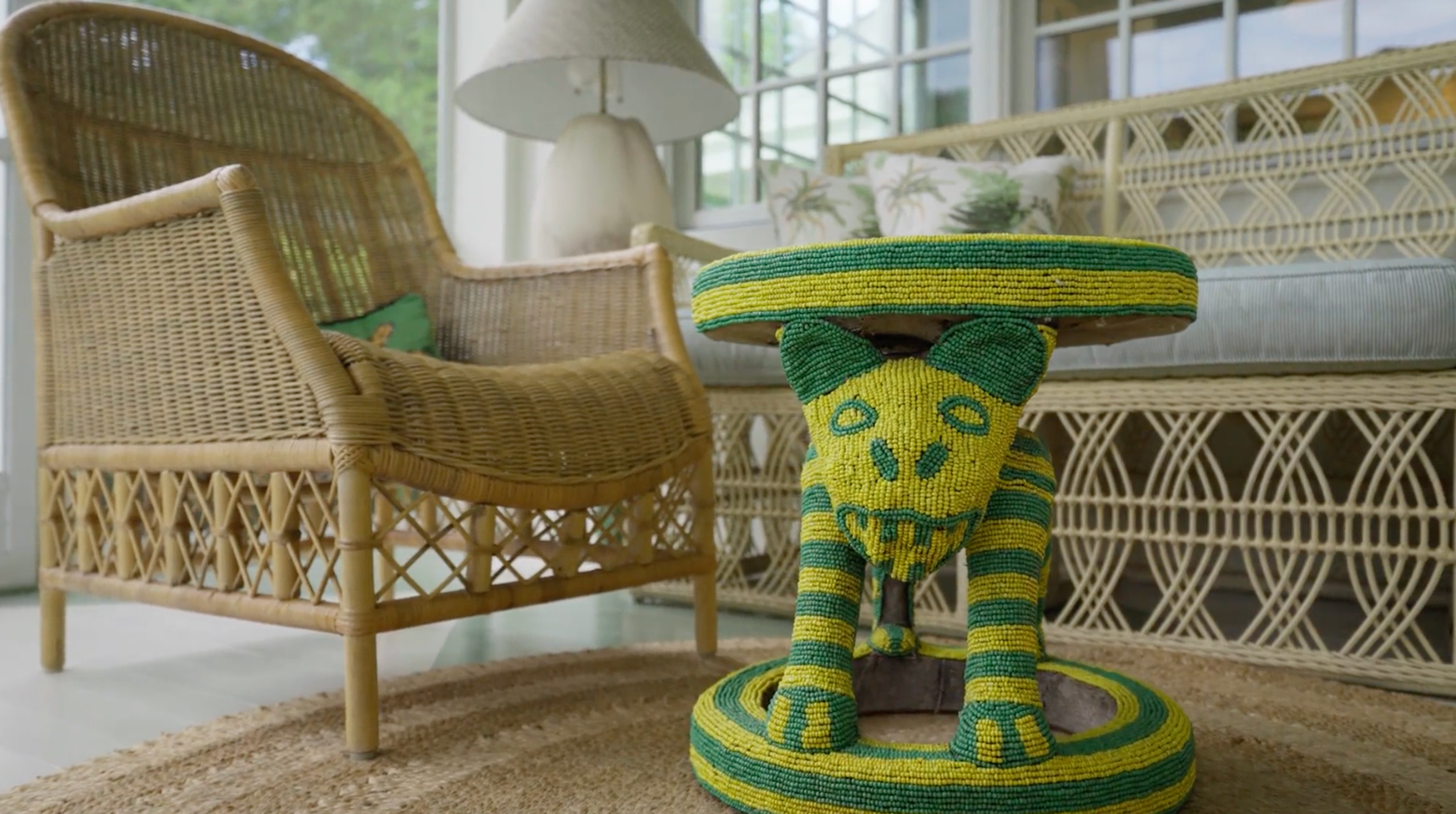 A comfortable sitting area on a covered porch with rattan furniture and plush cushions.
