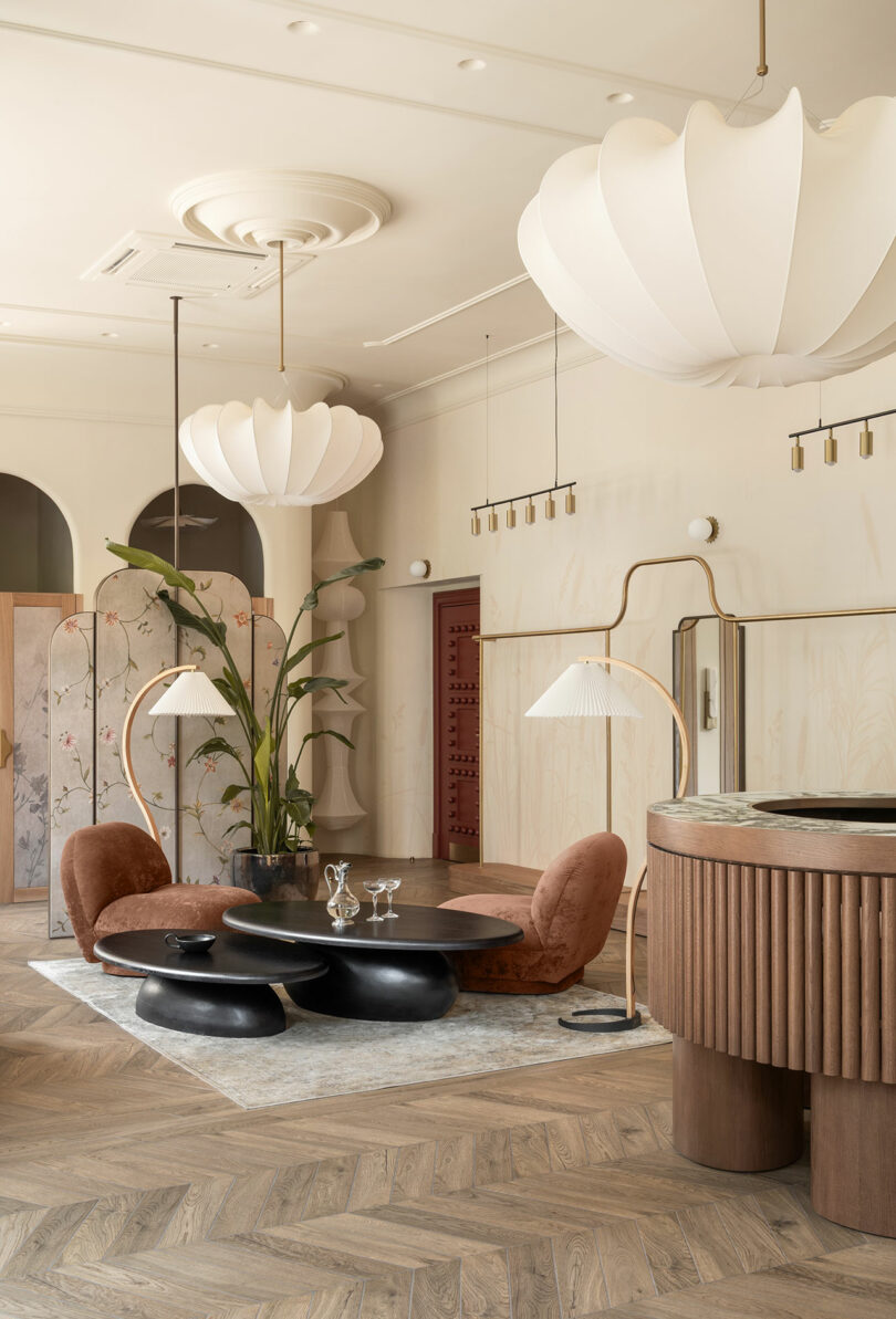 Modern lounge area within the boutique featuring chevron wood flooring and sculptural furniture.