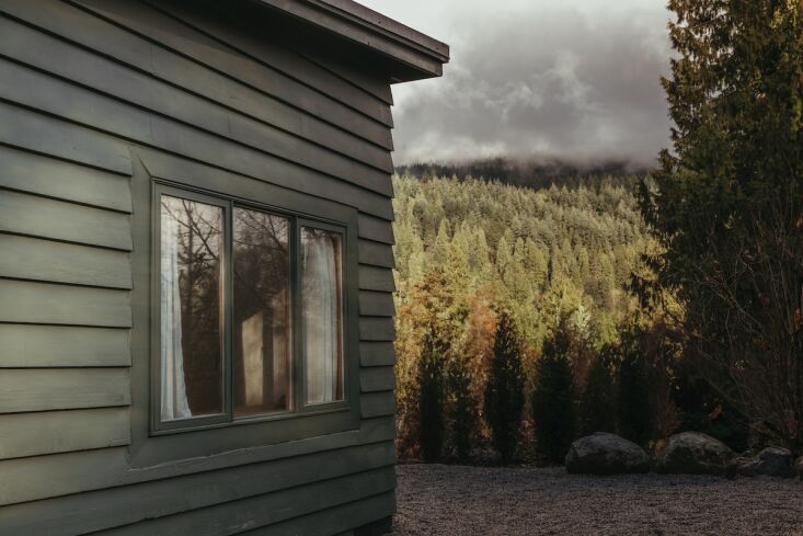 The dirt road leading to the cabin with snow-capped mountains visible in the distance.