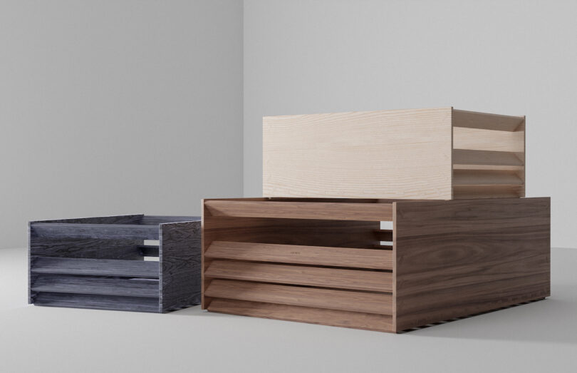 Three stacked wooden crates in dark grey, medium brown, and light beige tones.