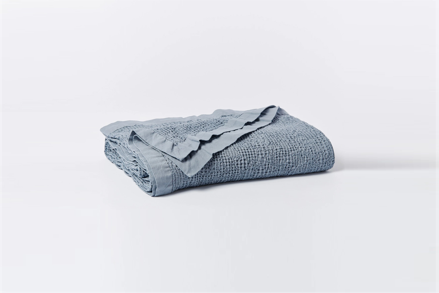 Steel blue organic waffle-weave cotton blanket showing deep honeycomb texture.