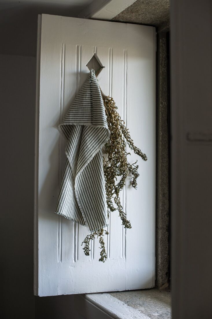 A set of two tea towels, one with bold vertical stripes and one plain natural cotton.