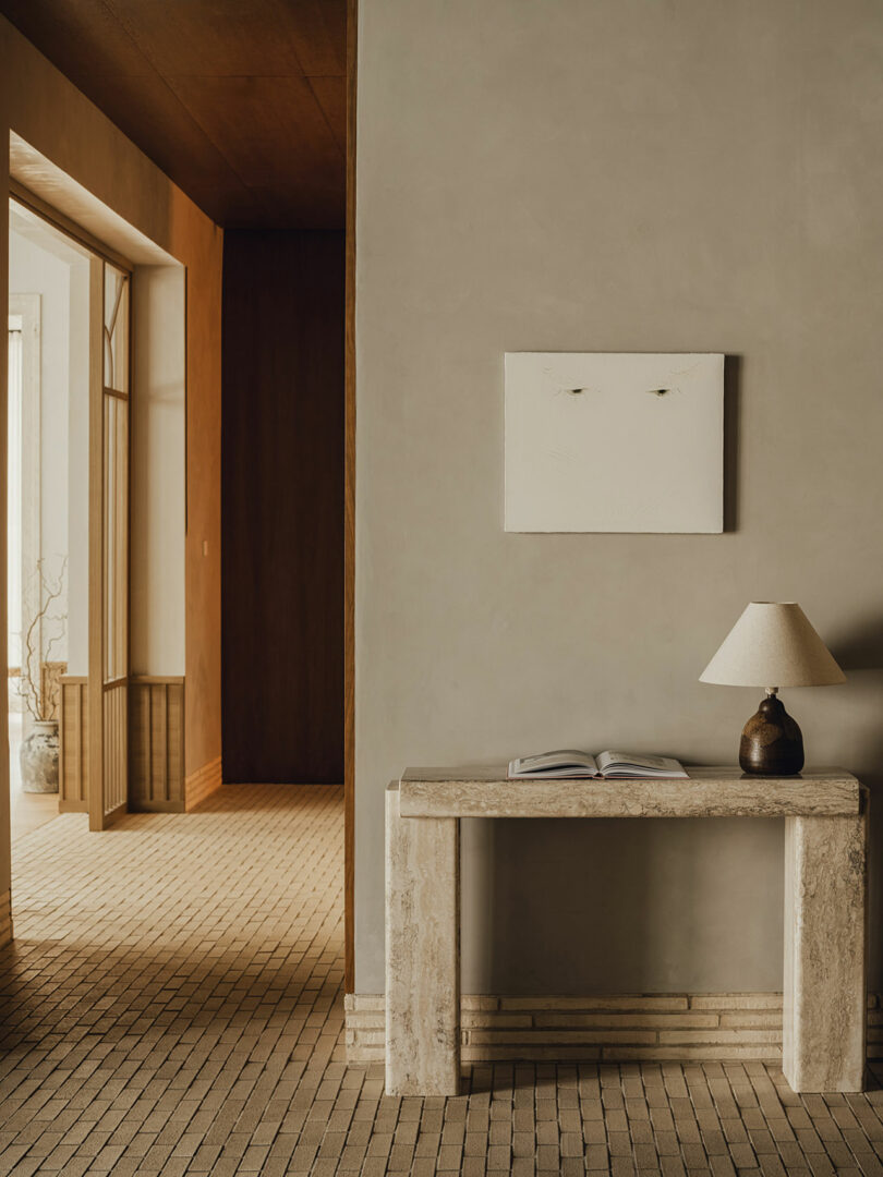 Minimalist hallway in Puro Hotel with a stone console, ceramic lamp, and neutral beige walls.