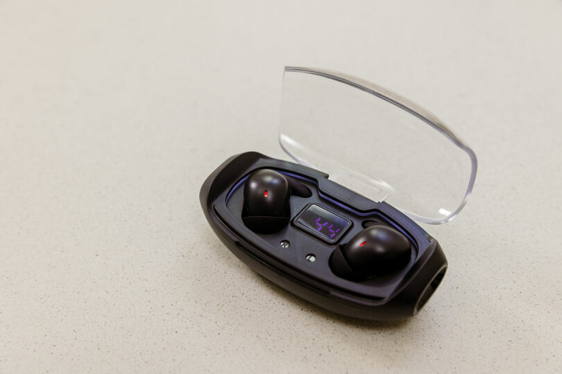 Black wireless earbuds inside a transparent charging case showing a 78 percent digital battery level.