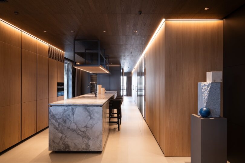 A high-end kitchen featuring a marble island contrasted with warm vertical wood cabinetry.