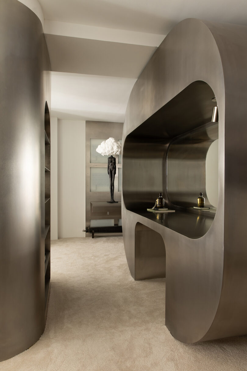 Interior view showing a desk area with curved metallic structures and artistic sculptures.