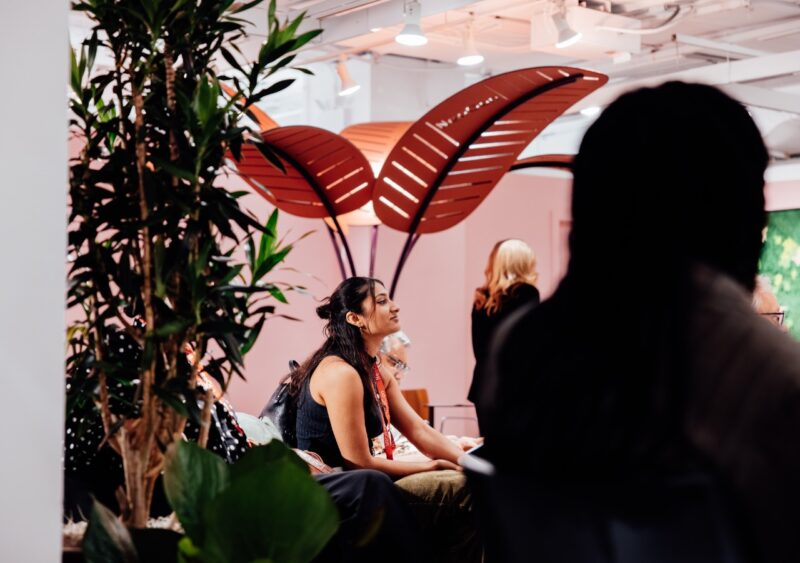 A woman sitting in a modern lounge area featuring large leaf-shaped privacy structures.
