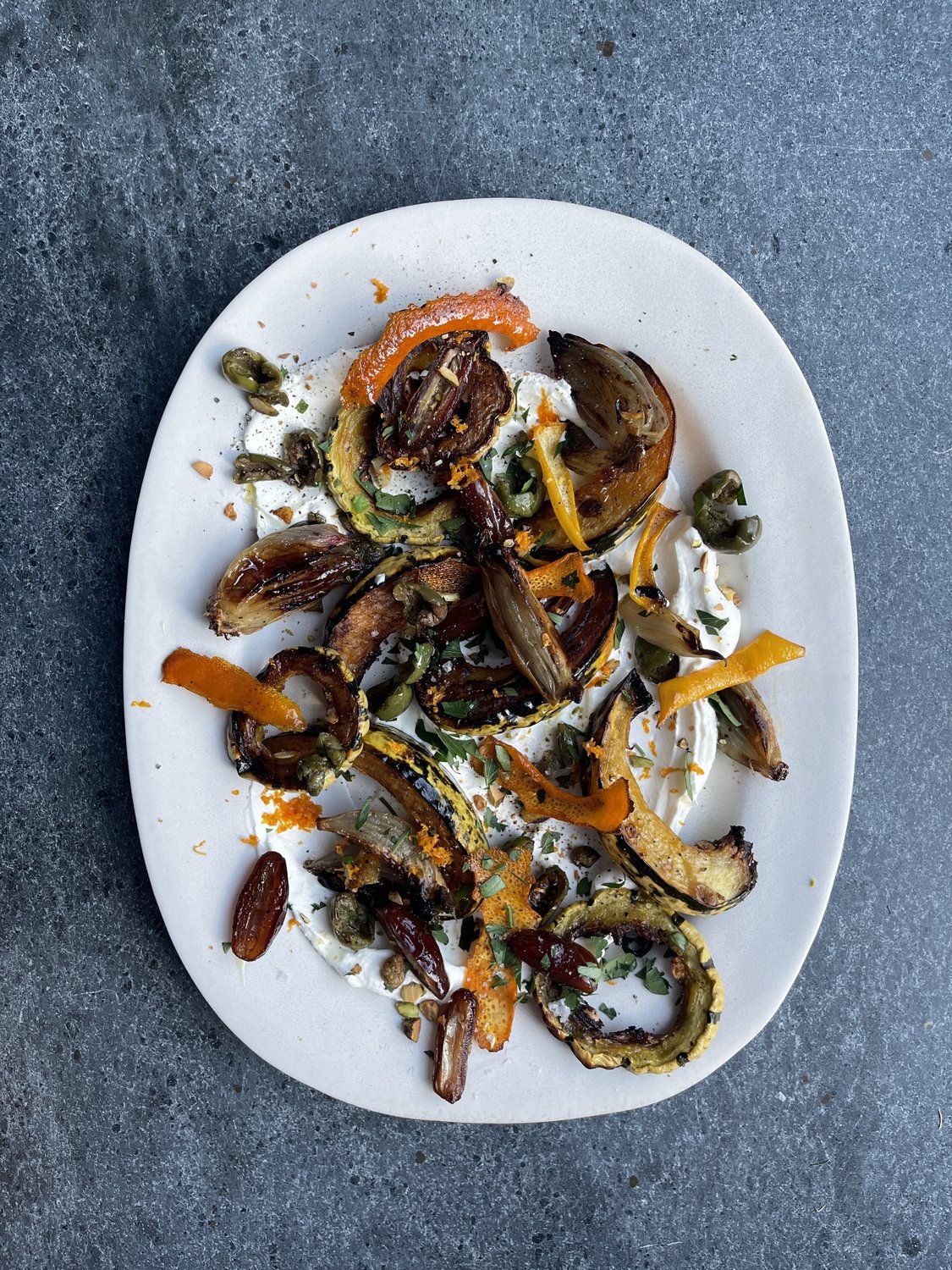 Whole delicata squash with yellow and green stripes sitting on a wooden surface.