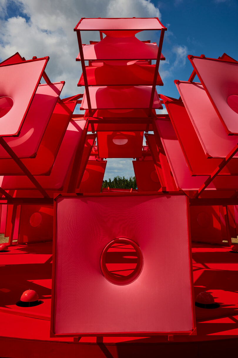 Stacked red square panels with circular cutouts creating a geometric sculpture.