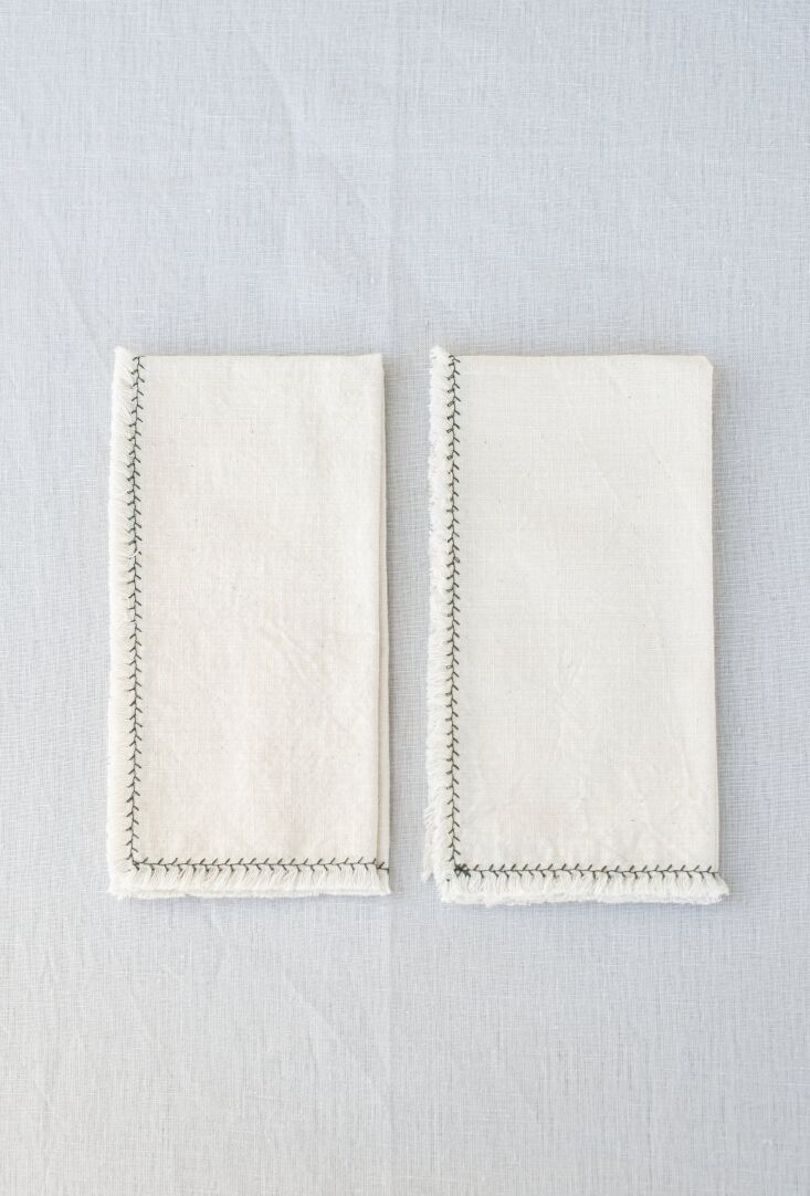 Cotton Flamé Natural Napkins featuring a raw edge and distinctive green zigzag stitching.