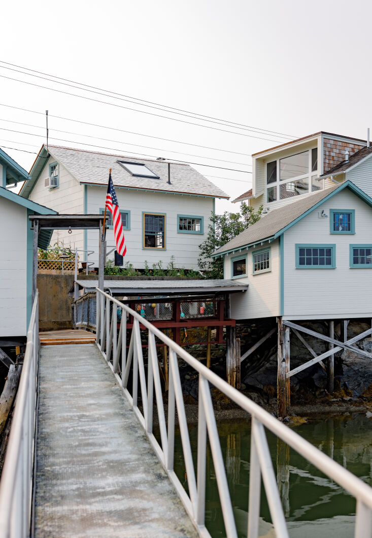 A cluster of weathered wooden buildings on a Maine dock with a skylight visible on the main kitchen structure.