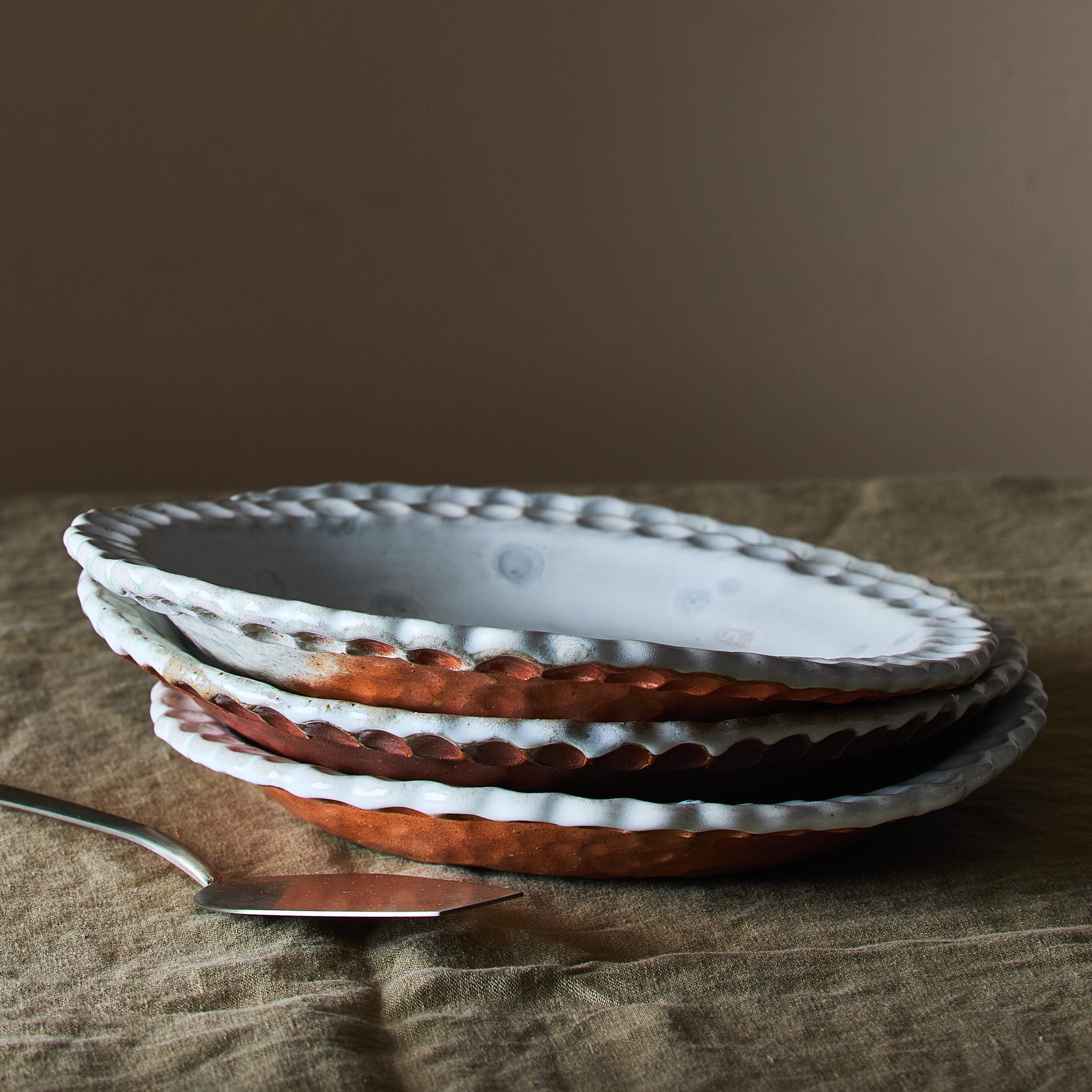 A stack of various wood-fired ceramic pie plates showing different shades of orange, red, and brown.