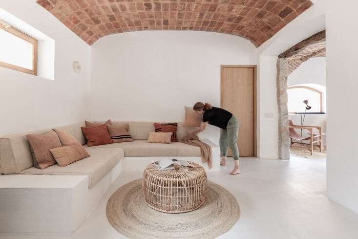 A built-in sofa with raw linen cushions in a minimalist, sunlit room.