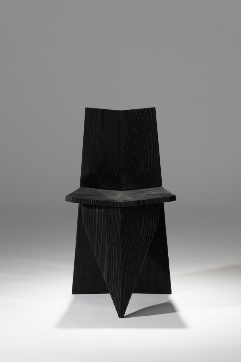 Front view of the black angular wooden chair, emphasizing its symmetrical and architectural silhouette.