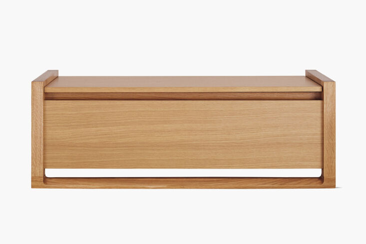 A low-profile walnut storage bench with integrated slit handles and a modern aesthetic.