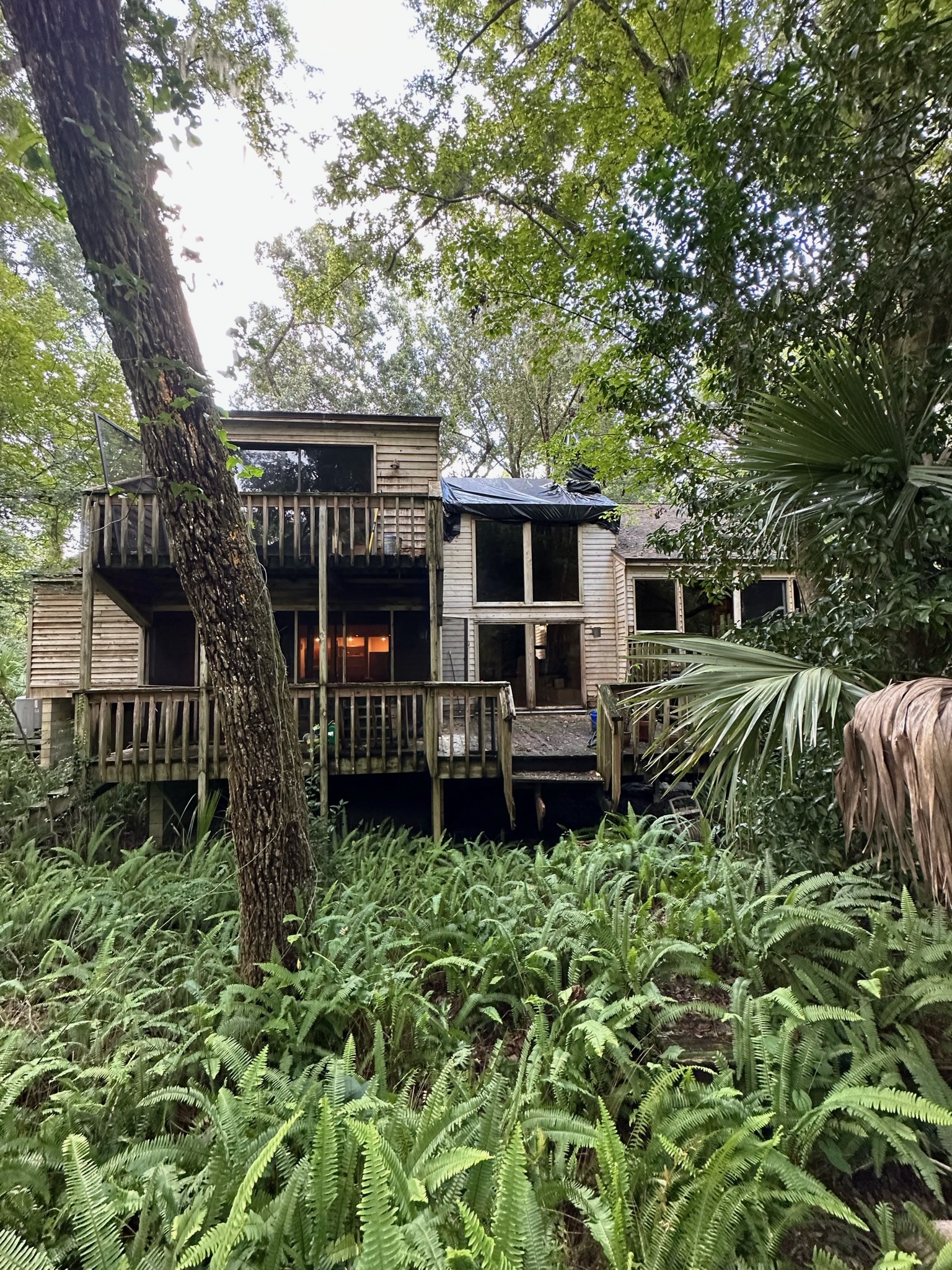 The original state of the house with rotting decks, water damage, and a tarp on the roof.