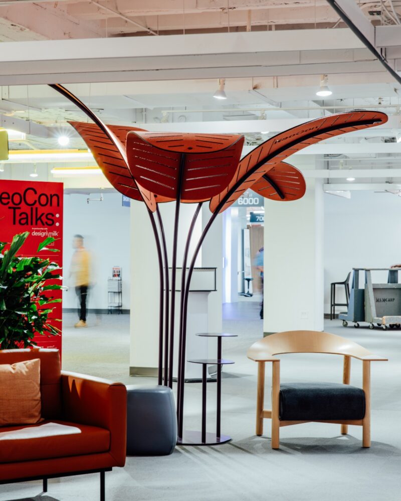 Modern office space with a large red and black sculptural leaf installation and comfortable seating.
