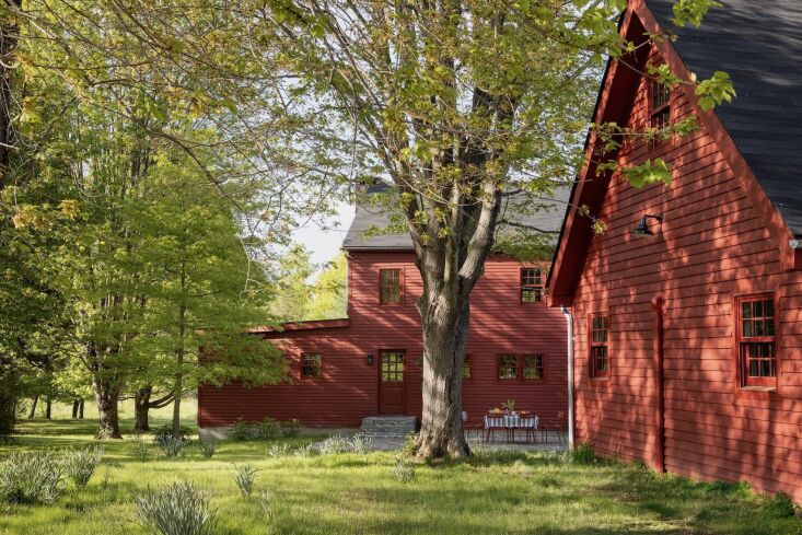 View from the back terrace looking toward a barn-red cottage and surrounding meadows.
