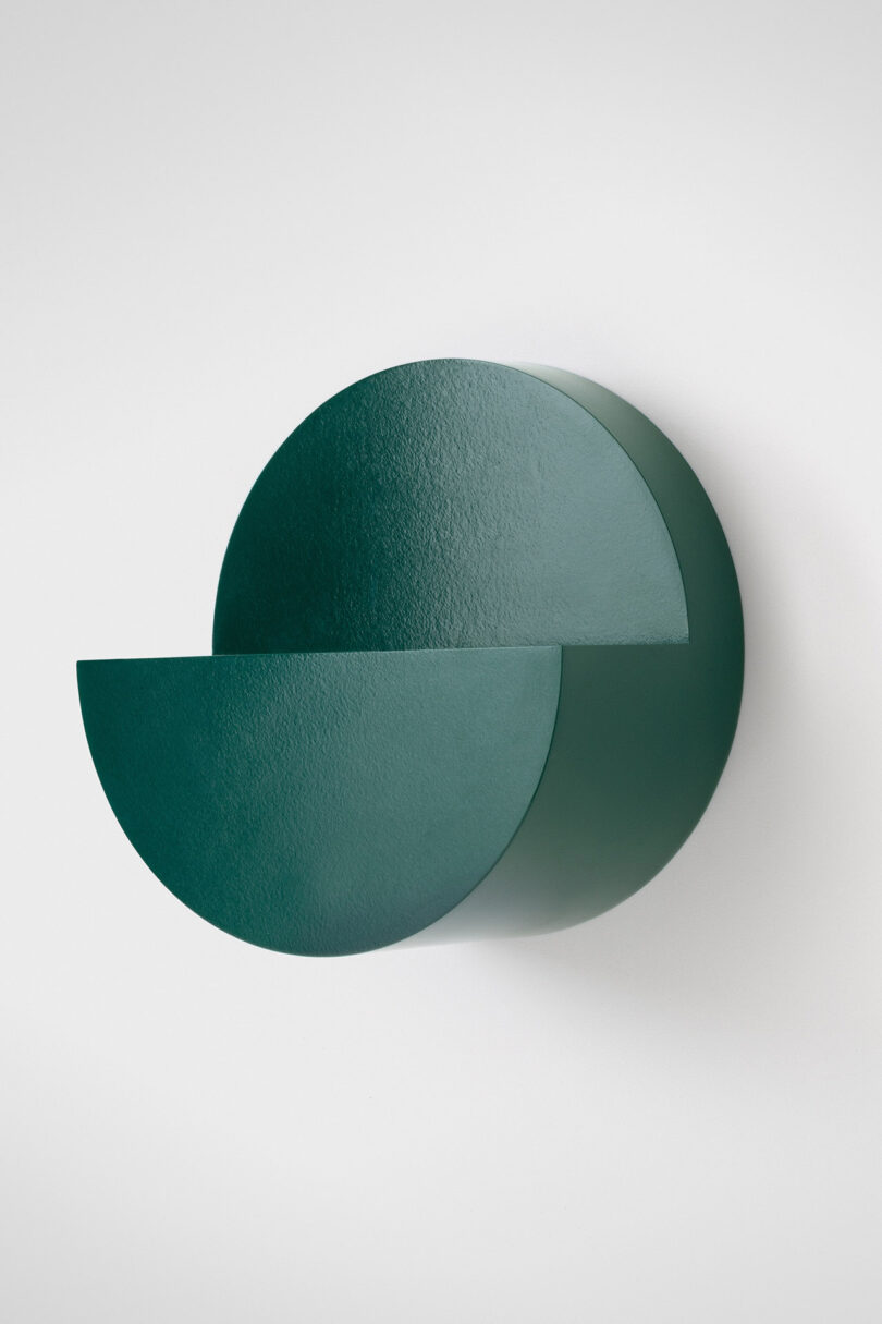 A dark green wall-mounted fixture with overlapping semicircular shapes.