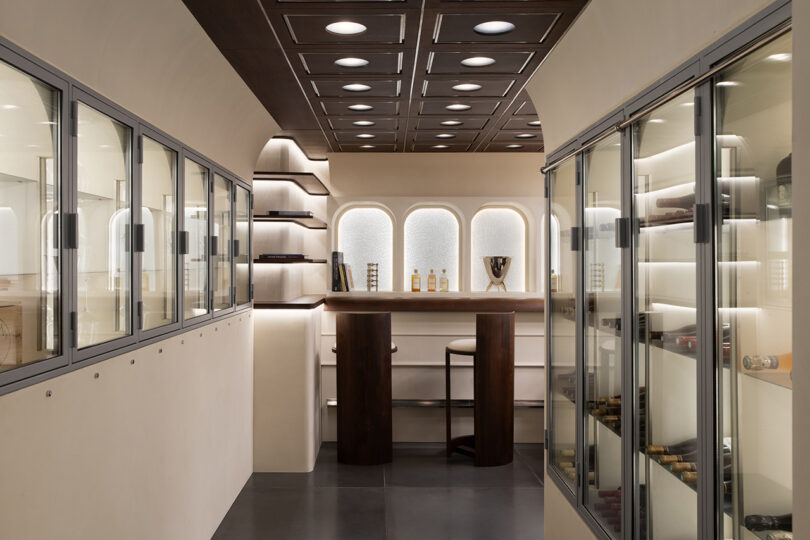 A sleek modern wine tasting room with glass-enclosed storage and recessed lighting.