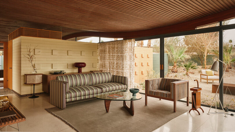 Detailed view of a living room with a colorful striped sofa and wooden mid-century furniture.