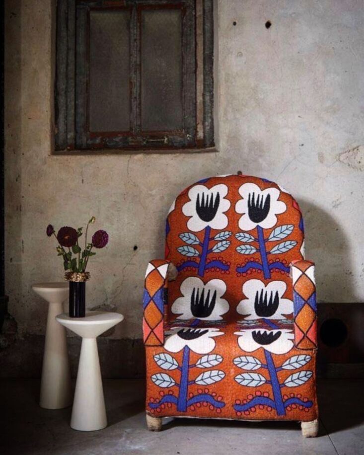 A colorful Yoruba beaded chair featuring bird and animal motifs on a dark background.