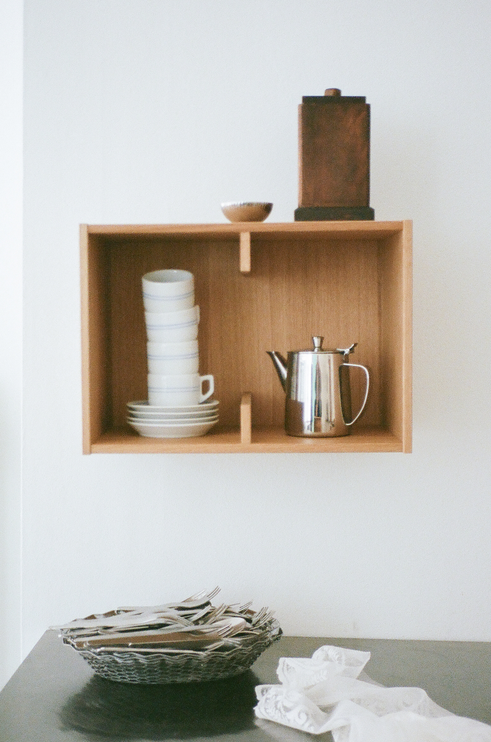A Sætter Shelf 2 in oiled oak used as a wall-mounted nightstand holding books.