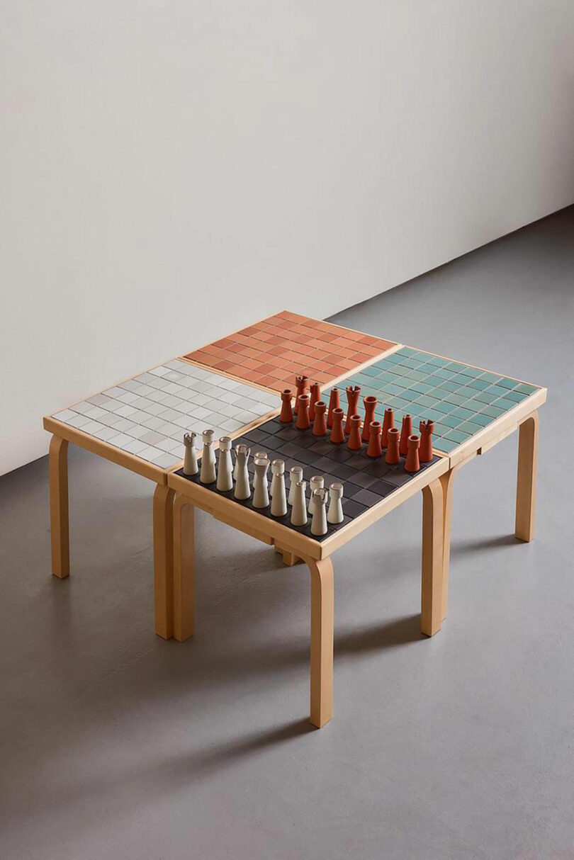 A limited-edition Artek x Heath chess table with ceramic pieces arranged on a tiled 8x8 grid.