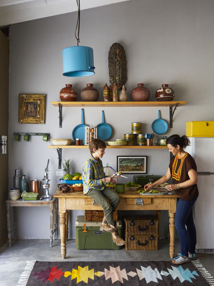 A turquoise enamelware stock pot converted into a rustic pendant lamp hanging in a kitchen.