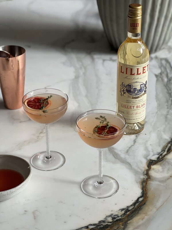 A close-up of a stylishly arranged bar cart featuring a stainless steel shaker and minimalist decor.