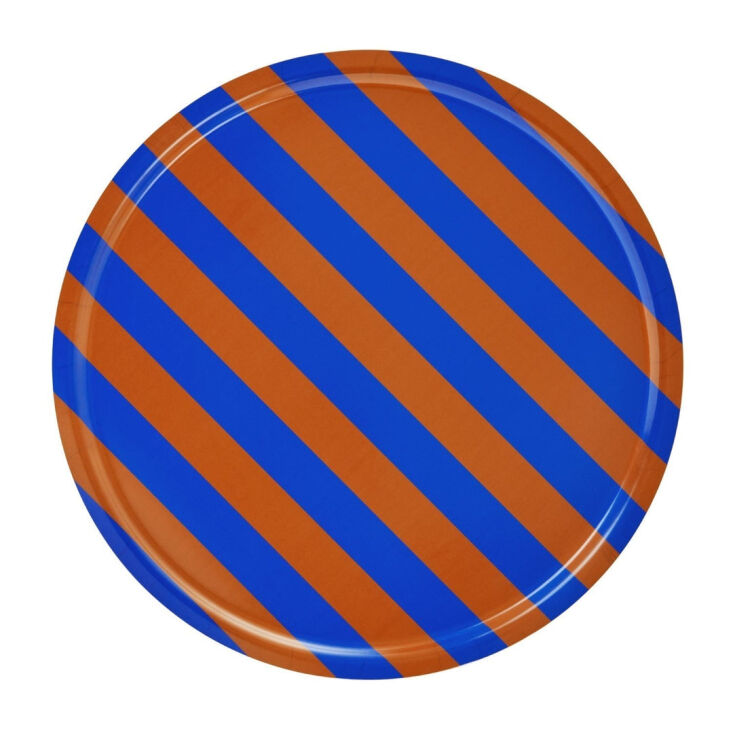 A large round birch tray with terracotta and cobalt blue stripes designed by Arthur Arbesser.